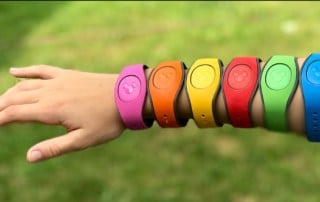 An outstretched child's arm adorned with Disney's magic bands in every color of the rainbow.