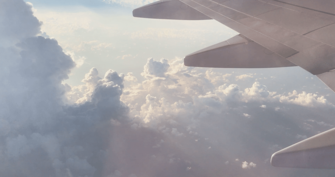 In flight view View of clouds under the wing of a plane, taken while peering out the airplane window.